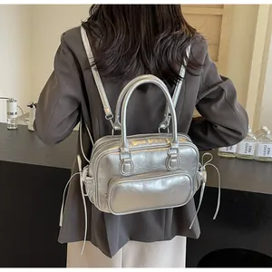 Silver metallic backpack with ruched texture shown on a model in a cafe setting