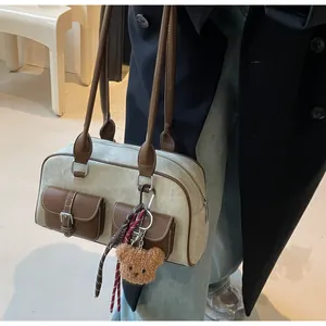 Detail of grey suede Boston bag with brown leather accents and a plush bear charm