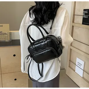Detailed back view of a woman wearing the black glossy convertible backpack and handbag