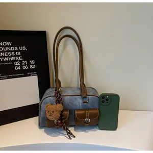 Close-up of retro blue Boston bag with brown leather handles and plush bear charm