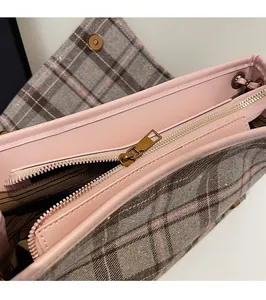 Close-up of golden zipper and pink leather trim on checkered fabric tote bag