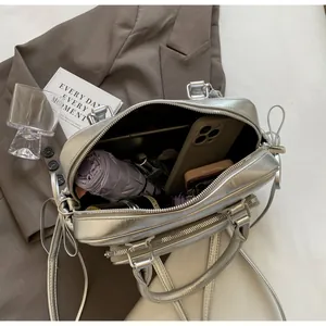 Interior view showing the large capacity of a silver metallic crossbody bag with accessories