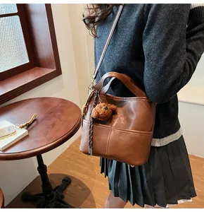 Close-up of brown litchi pattern bucket bag with a cute plush puppy pendant