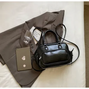 Detail of black glossy handbag with pleated texture and adjustable shoulder strap