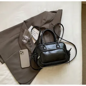 Detail of a black faux leather Boston bag with silver zippers and an adjustable strap