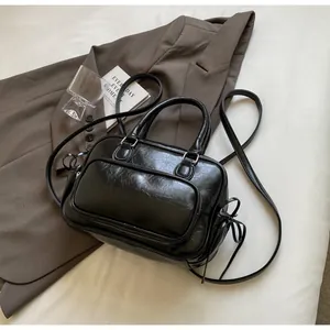 Detail of black retro wax leather handbag with side bow ties and dual zipper texture