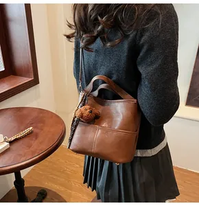 Brown vintage bucket bag with contrast stitching and a cute plush bear pendant accessory