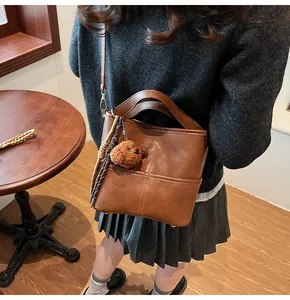 Brown leather crossbody bucket bag with handle and cute plush dog pendant detail