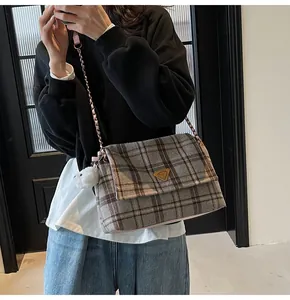 Close-up of grey and coffee plaid wool tote bag with golden metal logo and plush charm