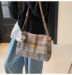 Detail view of large plaid tote bag with gold chain strap and cute dog plush charm