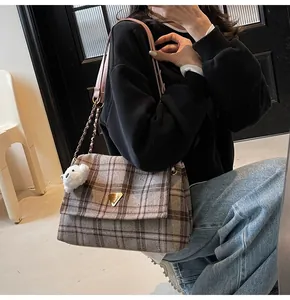 Close-up of retro plaid fabric shoulder bag with gold metal logo and plush bear charm