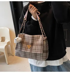 Detail of plaid tweed shoulder bag with metal chain strap and cute bear charm