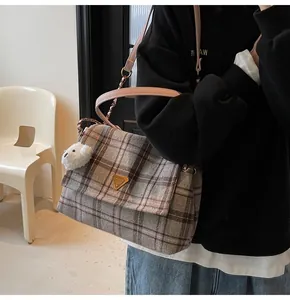 Detail of checkered tote bag featuring pink leather strap and cute bear charm accessory