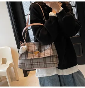 Detailed close-up of plaid fabric tote bag with pink straps and cute sheep pendant