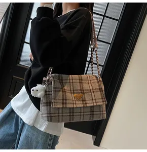 Detail of British style plaid crossbody bag with gold triangular buckle and plush charm