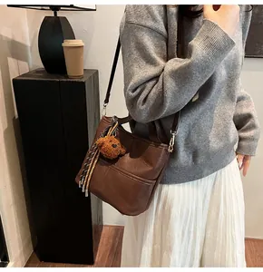Detail of dark brown tote bag with pebble leather texture and cute teddy bear charm