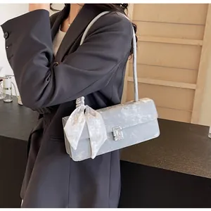 Dettaglio borsa a spalla azzurra con fibbia metallica argento e foulard di seta bianco
