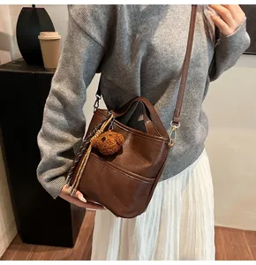 Brown leather bucket bag styled with a gray sweater and cute plush bear charm