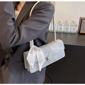 Dettaglio della borsa a spalla blu metallizzato con fibbia di strass e foulard a scacchi