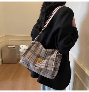 Detail of grey plaid tweed tote bag with plush dog charm and pink leather chain strap