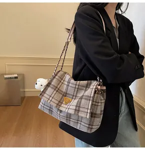 Close-up of retro plaid tote bag with metal triangle logo and white plush bear charm