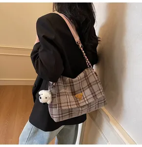 Detail of plaid tweed shoulder bag featuring a pink leather chain strap and cute dog charm