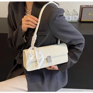 Dettaglio borsa baguette color crema con fibbia di strass e tracolla foulard