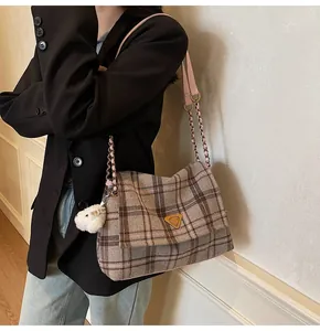 Detail of plaid tote bag with golden triangle logo and pink leather chain strap