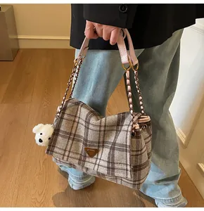 Detail of plaid tote bag with pink leather handles, gold chain and white puppy charm