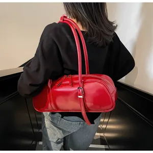 Close-up of a glossy red baguette bag with silver buckles and a dual zipper detail