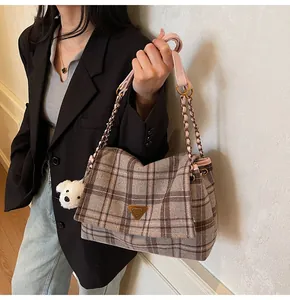 Detail of plaid tweed tote with golden triangle plaque and plush dog charm