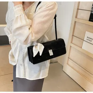 Dettaglio borsa sottobraccio in velluto nero con foulard di seta sulla tracolla