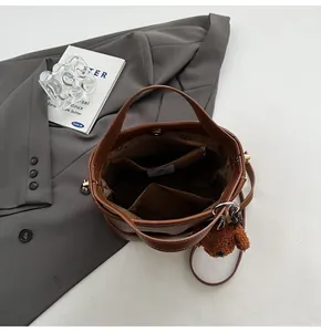 Detailed interior of a brown leather bucket bag featuring pockets and a plush bear charm