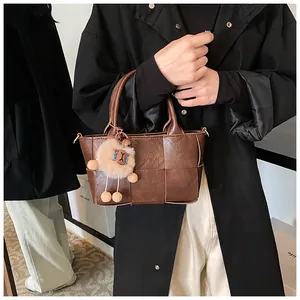 Détail du sac cabas tissé marron foncé avec un charmant mouton en peluche sur un manteau