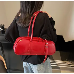 Close-up of vibrant red patent leather cylinder bag with sleek glossy finish and straps