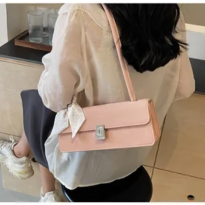Dettaglio borsa a spalla rosa con fibbia di strass e sciarpa decorativa a pois bianchi