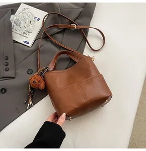 Close-up of brown bucket bag with golden base studs and cute plush bear charm
