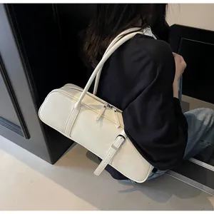 Detail of cream glossy baguette bag featuring dual zippers and sleek leather straps