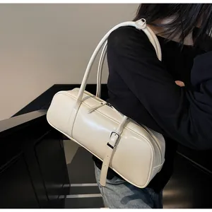 Detailed view of cream baguette bag with metallic buckles and sleek leather finish