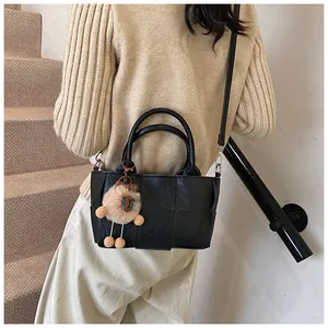 Détail d'un sac seau noir en cuir PU tressé avec pendentif en peluche et bandoulière