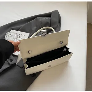 Interno della borsa a tracolla beige con due scomparti e fibbia magnetica argentata