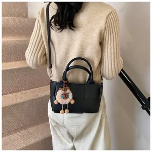 Détail d'un sac seau noir tressé avec breloque d'ours porté par un mannequin