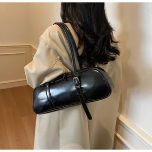 Detail of a black glossy leather baguette bag featuring an adjustable silver metal buckle
