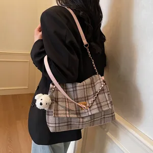 Winter plaid tote bag with pink leather strap and plush charm shown on a model