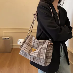Winter plaid tote bag with plush puppy pendant and metal hardware in a casual lifestyle setting