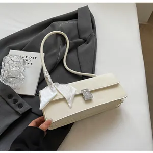Dettaglio borsa crema con fibbia argento e foulard decorativo in seta sulla tracolla