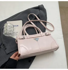 Detail view of pink glossy handbag with triangle metal plaque on grey blazer