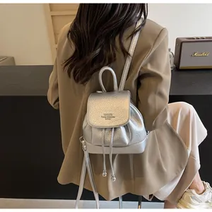 Detail of silver textured mini backpack with drawstring closure and magnetic flap