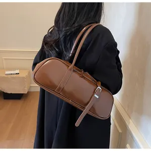 Detail view of deep brown glossy leather baguette bag featuring elegant side buckle accents