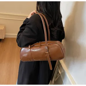 Close-up of a stylish glossy brown baguette bag featuring thin straps and metal buckle detail